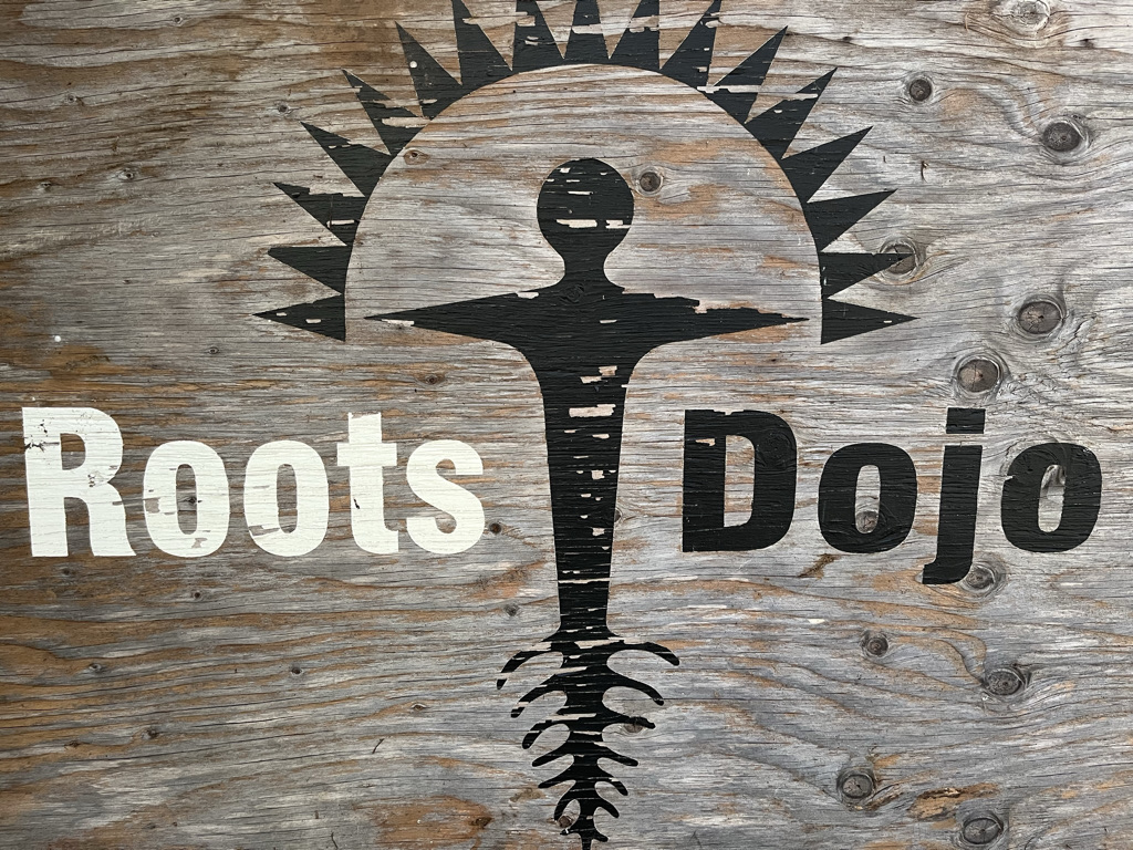 Weathered wooden Roots Dojo sign and emblem