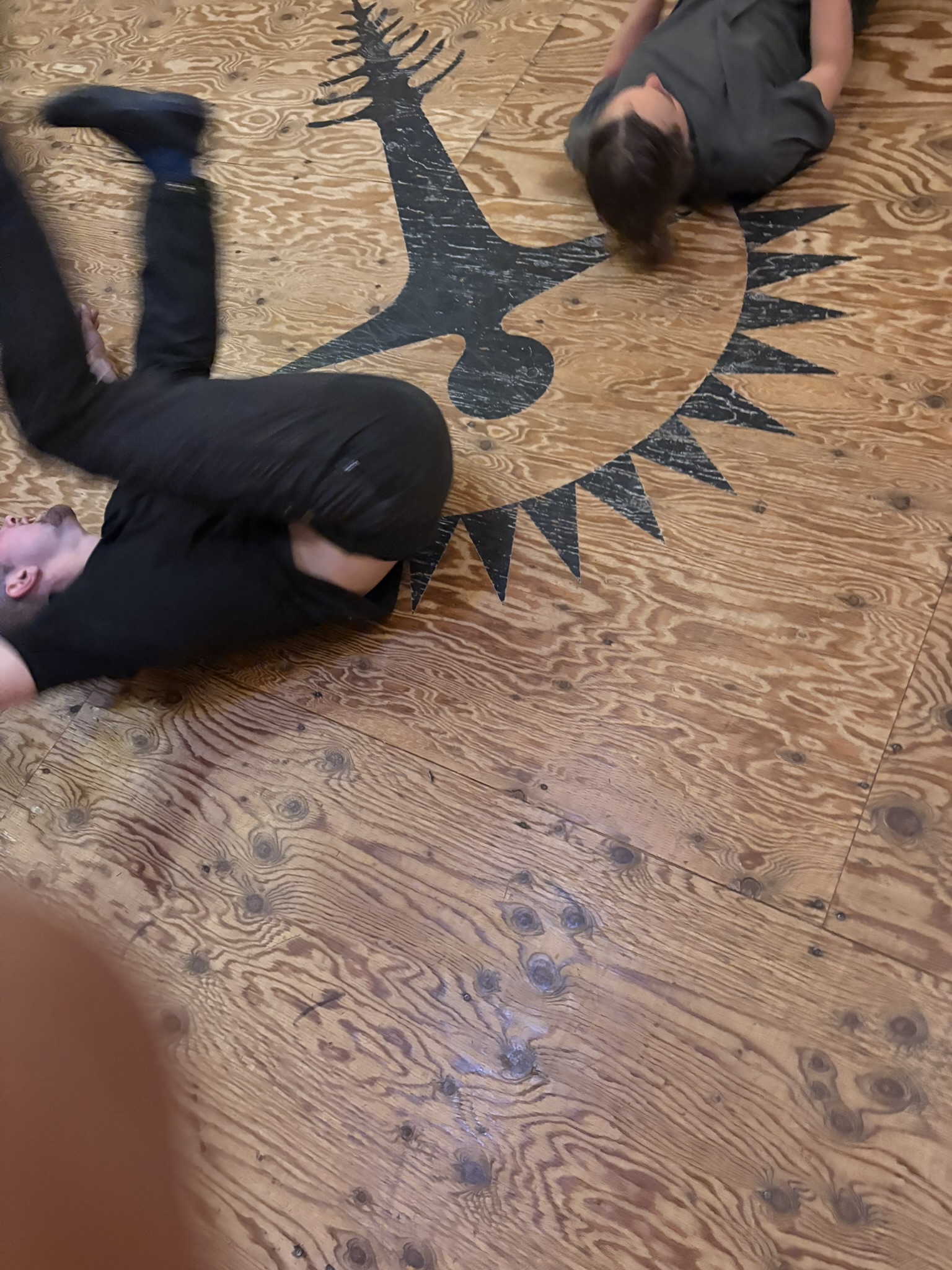 Two students practising ground movement beside the Roots emblem