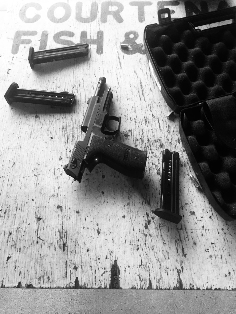 A pistol, magazines and an open case in a black-and-white photograph